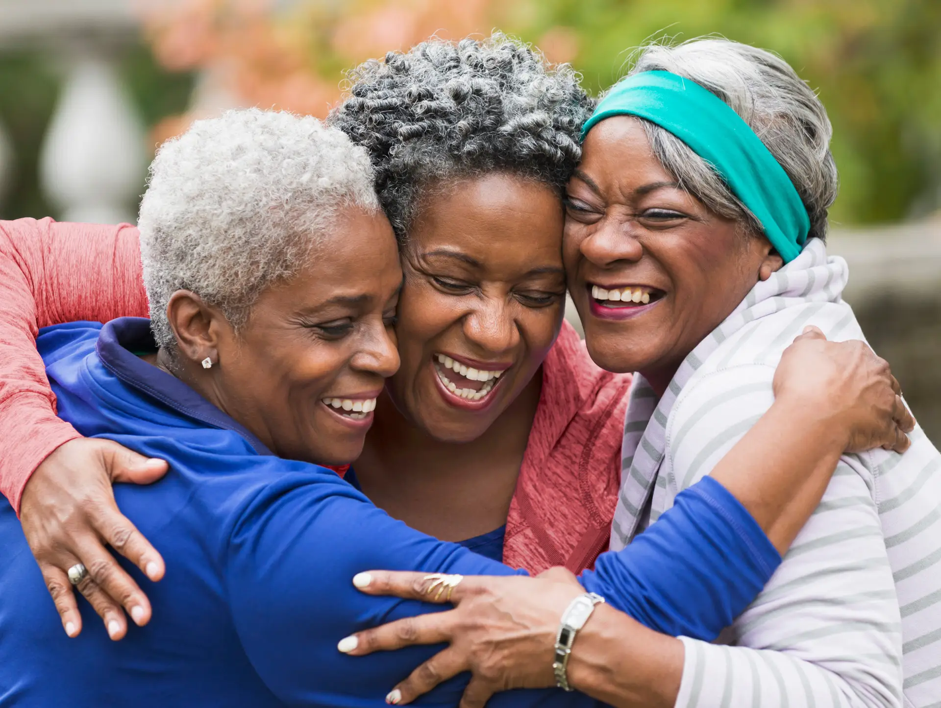 Tres mujeres mayores abrazadas y sonrientes