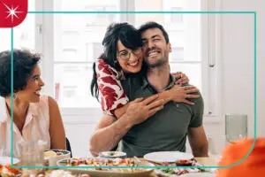 A woman hugs man at dinner table gathering with a Quartz spark and teal outline