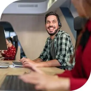 Two people working at computers. They are talking to each other and smiling.