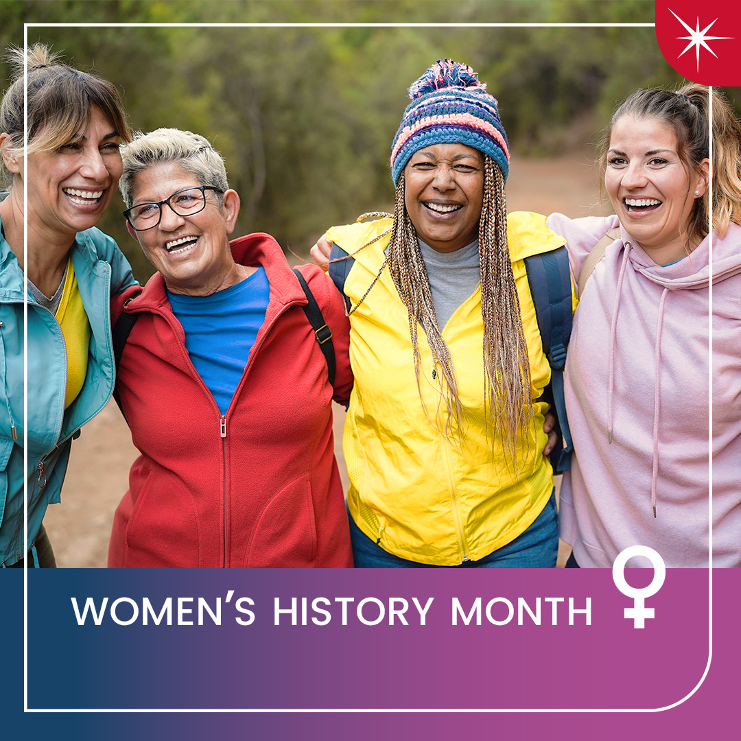 Four women in hiking gear hold each other up by the shoulders and laugh.