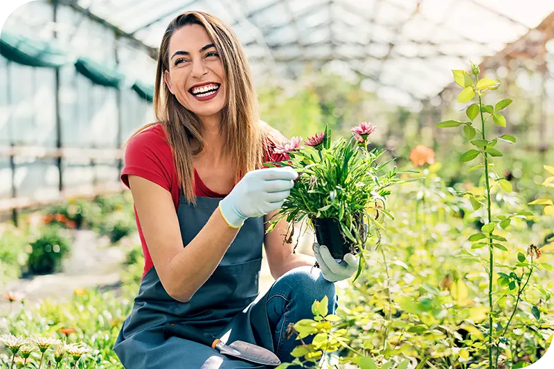 A person in a red shirt is gardening while smiling big.