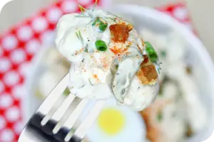 An image cauliflower potato salad recipe with chives and spices on top.