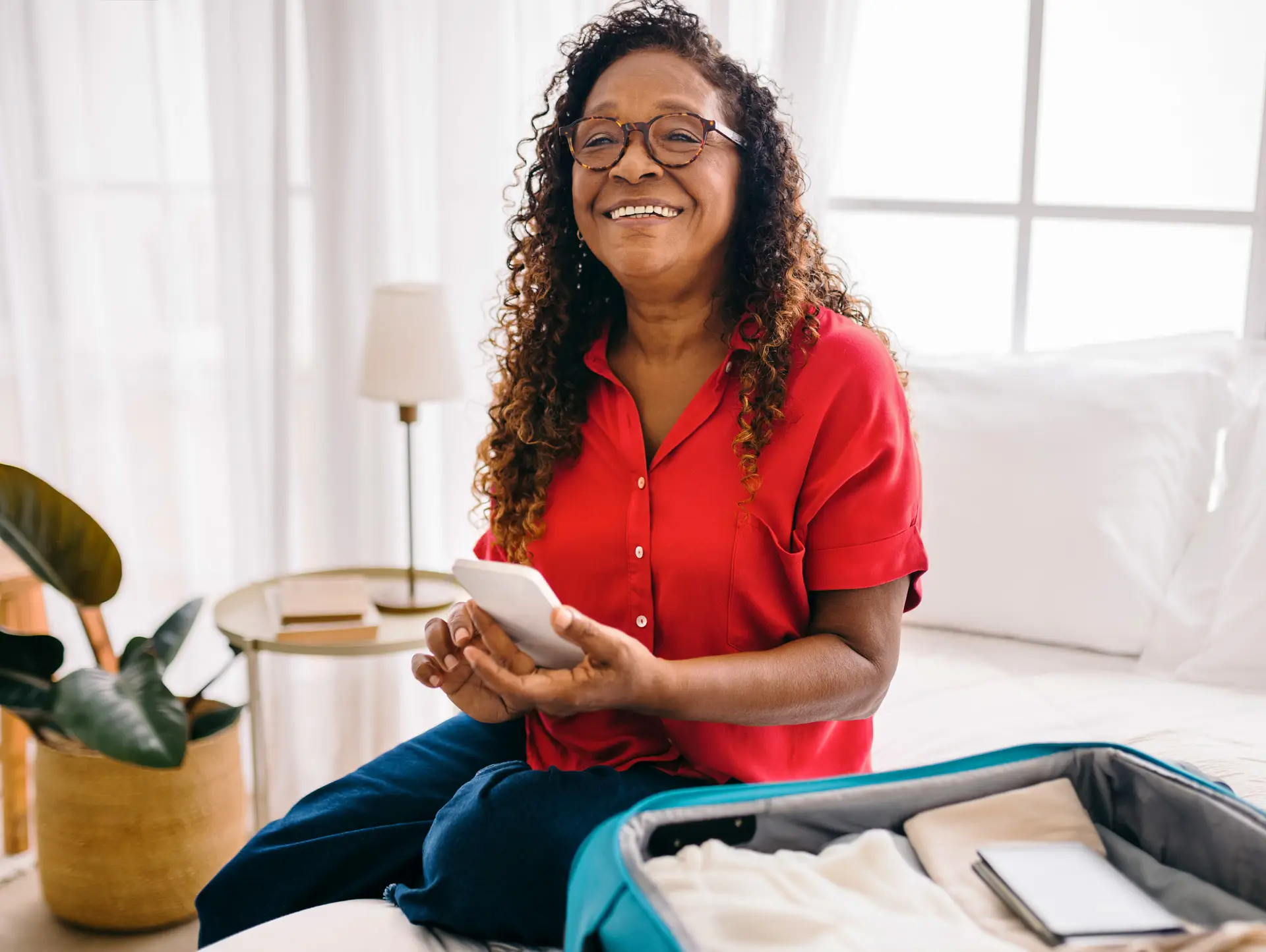 Senior woman sitting on a bed with an open suitcase