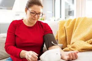 A person uses a blood pressure monitor while sitting on their couch