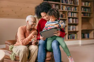 Three generation family sitting with tablet and laughing together