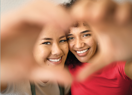 Two women creating a heart with their hands.
