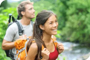 Two hikers look forward and smile by a river