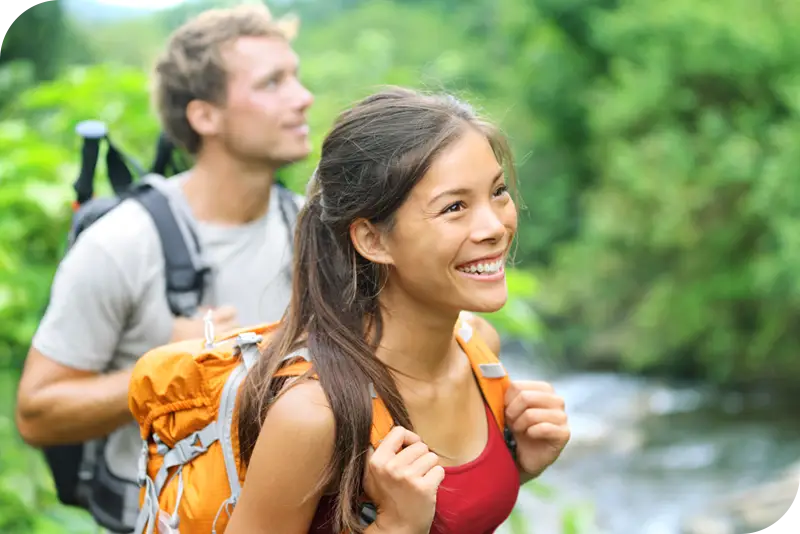 Two hikers look forward and smile by a river