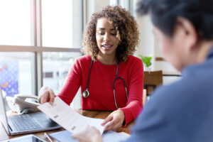 A health provider smiles as they show a patient a sheet of paper