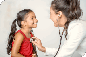 A healthcare provider checks a smiling child's heart rate as they make eye contact and share a warm moment.
