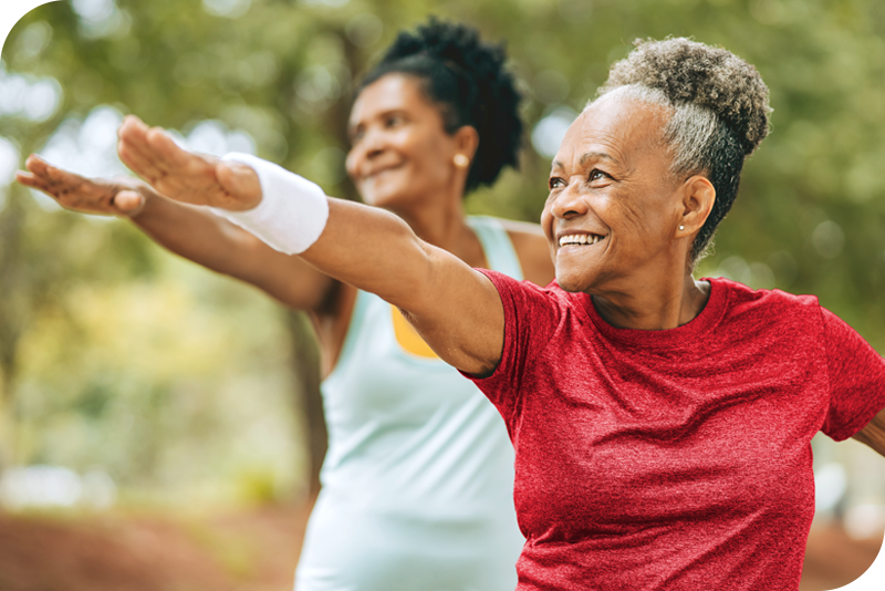 Two persons exercise in front of a lush green nature background