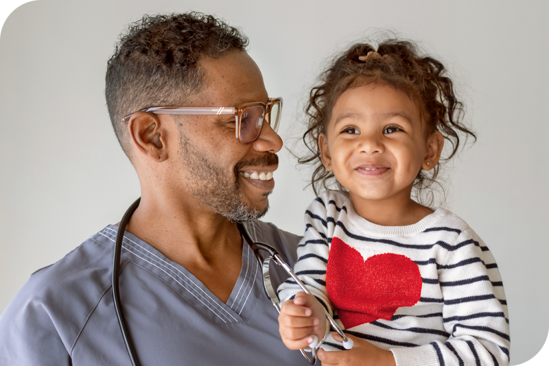 A health provider holds up a child as they both smile