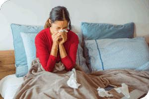 A person sitting in bed blowing their nose