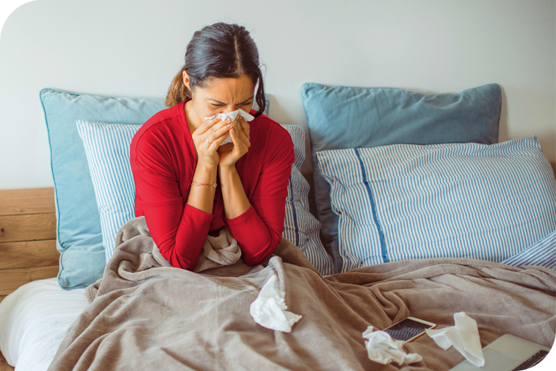 A person sitting in bed blowing their nose
