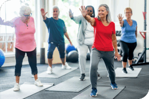 A group of people do aerobics in a brightly lit room