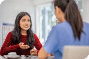 A person smiles as they sit in front of a care provider they appear to be having a conversation with