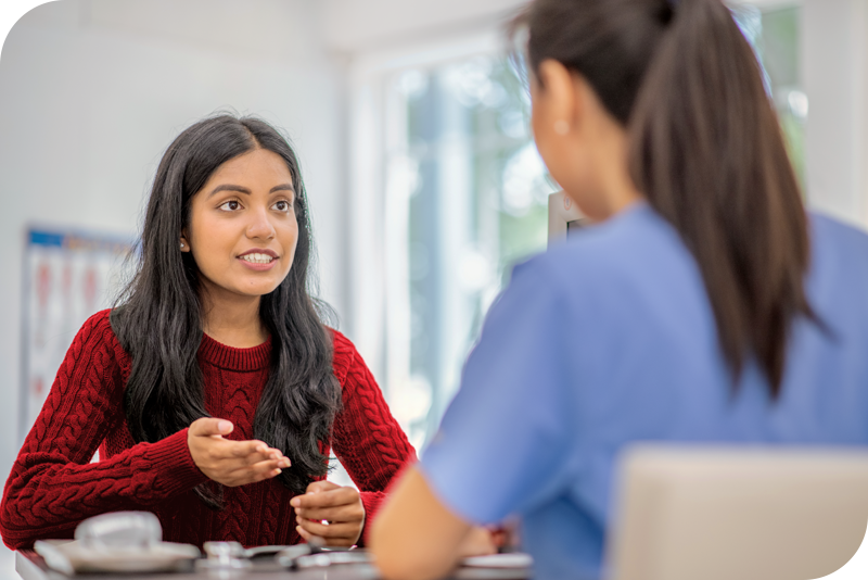 A person smiles as they sit in front of a care provider they appear to be having a conversation with