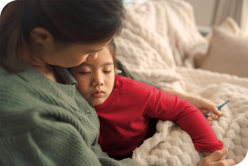 A young child sleeps in the arms of an adult