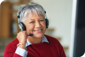 A person smiles as they look into the camera and have a headset and mike on