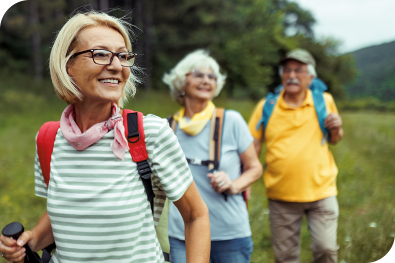 Group of people with walking sticks on a hike through the woods.