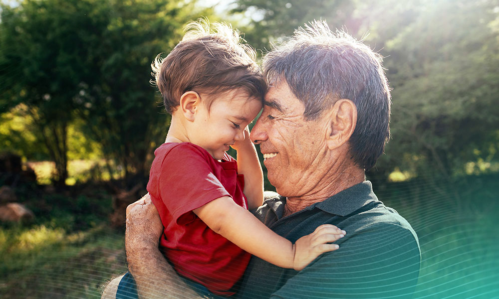 Playful grandfather spending time with his grandson in park on sunny day