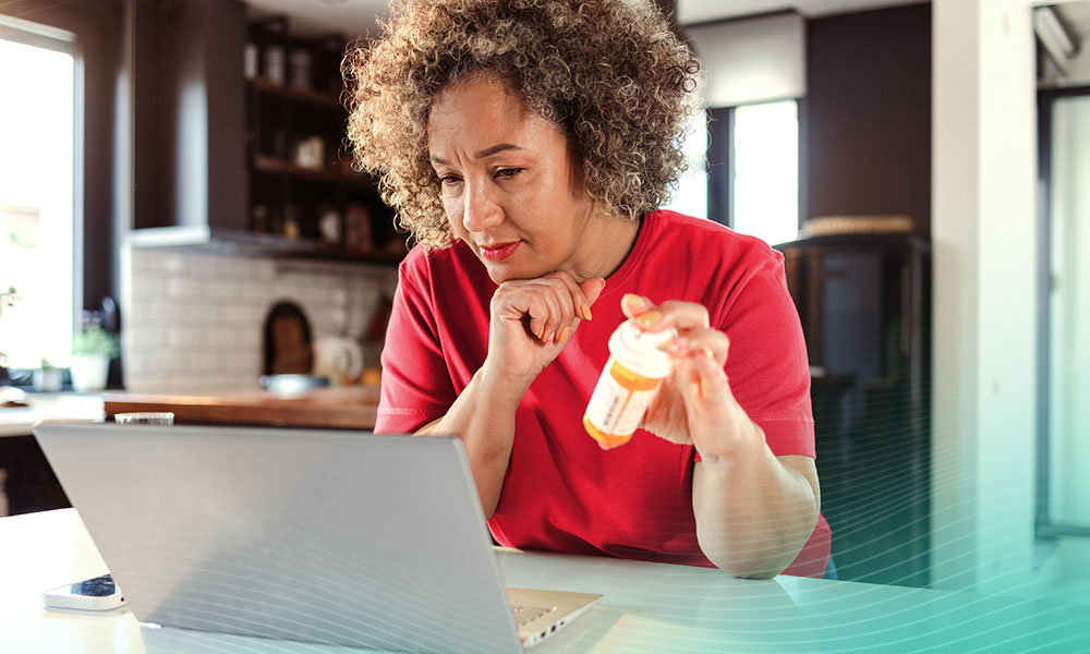Mature African American woman sitting at the table in the living room and searching information about medicine on the internet