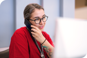 A woman talking on the phone while using a computer.