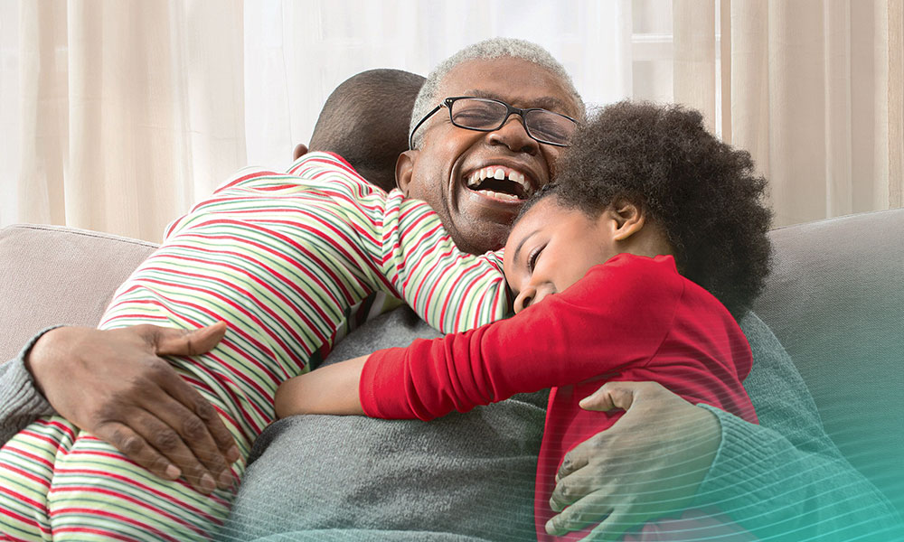 Older man hugging grandchildren on sofa