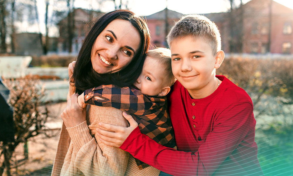 a happy mom plays with her two sons in a spring park.