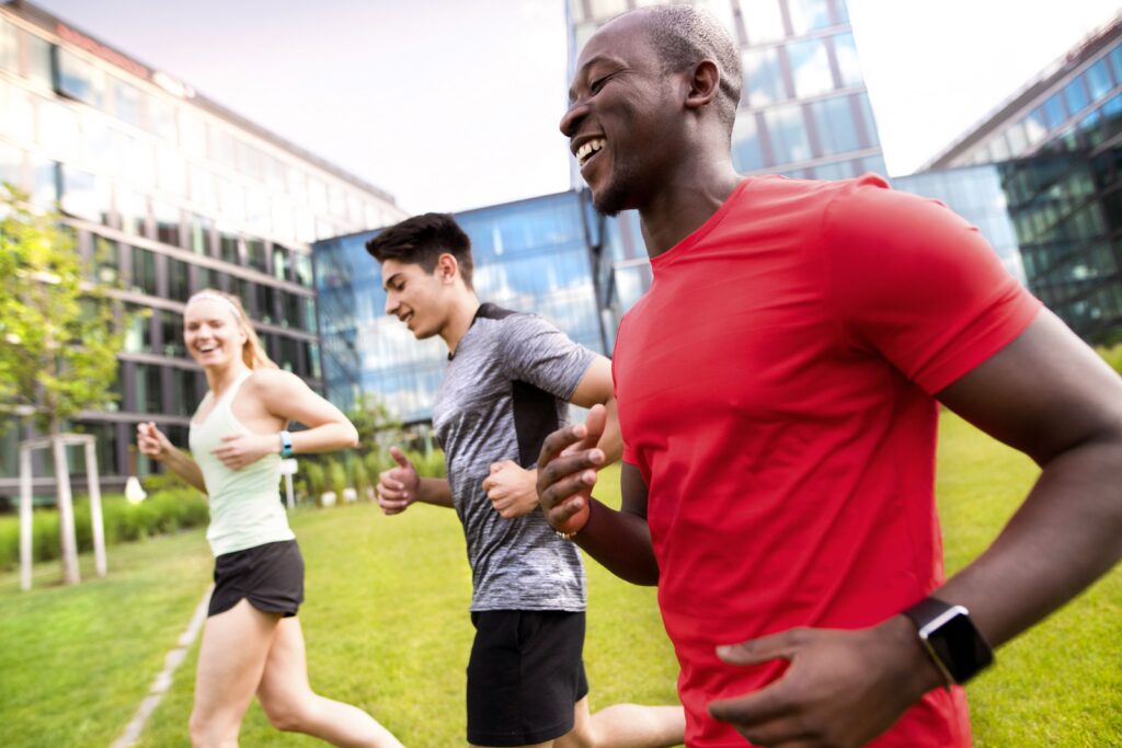 Beautiful young people running together in the city in front of glass buildings.