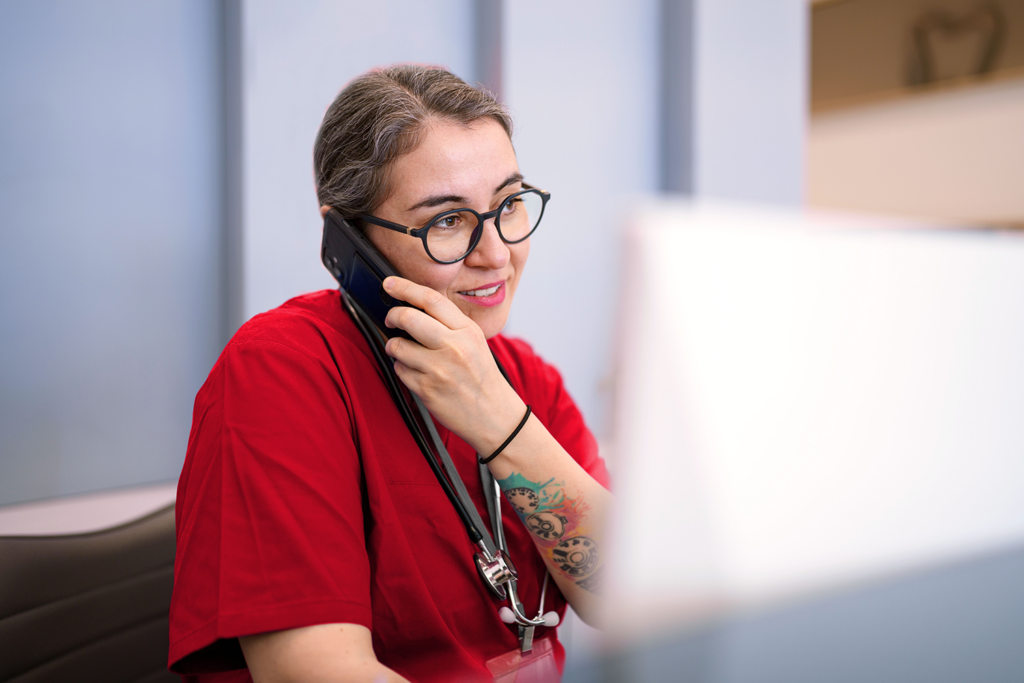 A healthcare worker sits at a desk, engaged in a conversation on the phone. The scene highlights the essential communication and administrative tasks healthcare professionals handle in a clinical environment.