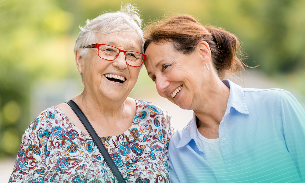 Senior mother and daughter hugging and smiling outside